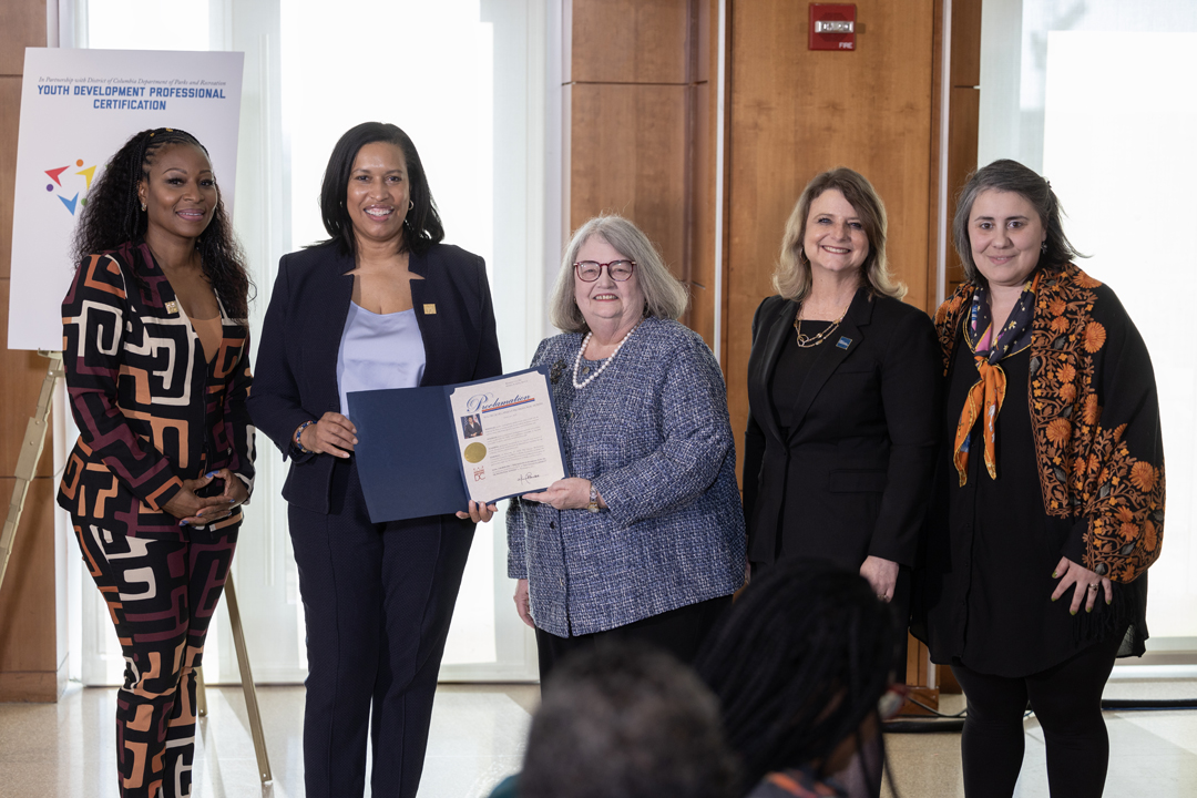 Thennie Freeman, Mayor Muriel Bowser, Natalie Houghtby-Haddon, Liesl Riddle, and Ina Gjikondi show off the mayoral proclamation of Youth Development Professional Month.