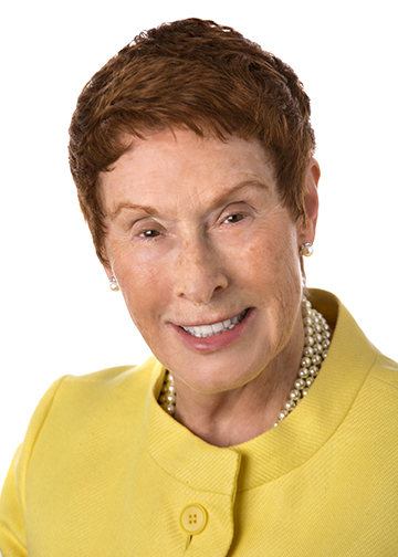 Headshot of woman with short red hair and yellow tailored suit jacket