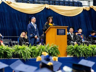 Christopher Linares with Tierney Pitzer at Commencement Celebration on the stage in regalia