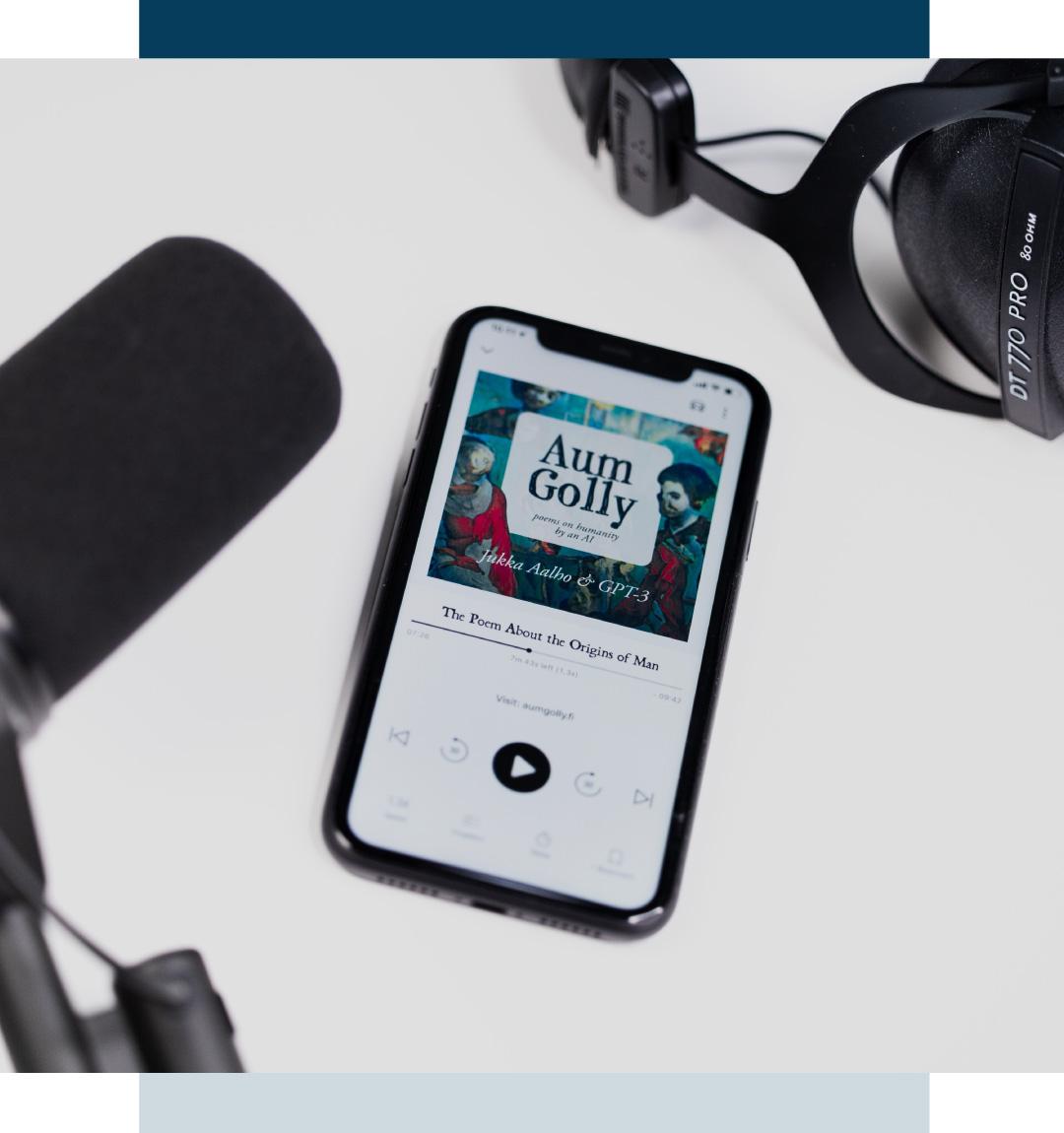 Microphones above a table, on the table a smartphone a podcast on it