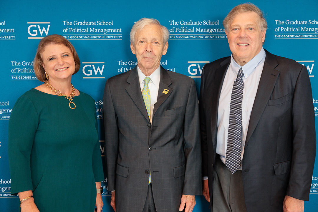 Dean Liesl Riddle, Dr. Christopher Arterton, and Mark Penn standing in front of a step-and-repeat