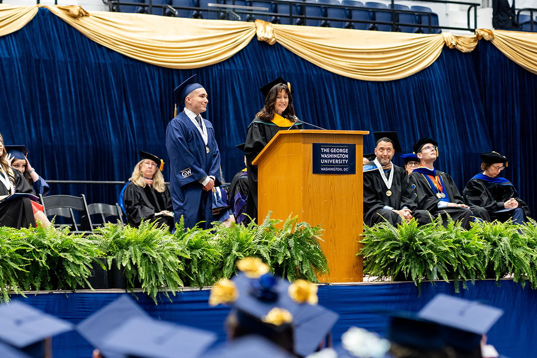 Christopher Linares with Tierney Pitzer at Commencement Celebration on the stage in regalia