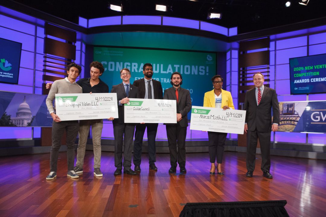 New Venture Competition winners standing onstage holding oversized checks