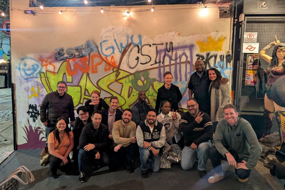 Students pose in front of graffitied wall