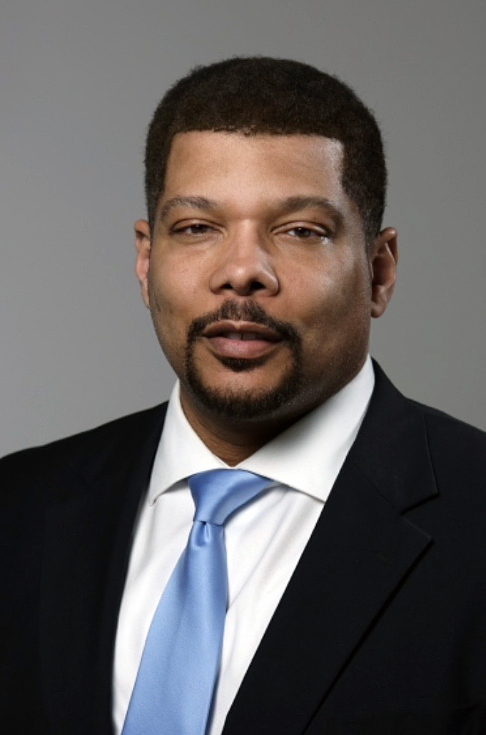 Adrian Black professional headshot photo in dark suit, white shirt and light blue tie