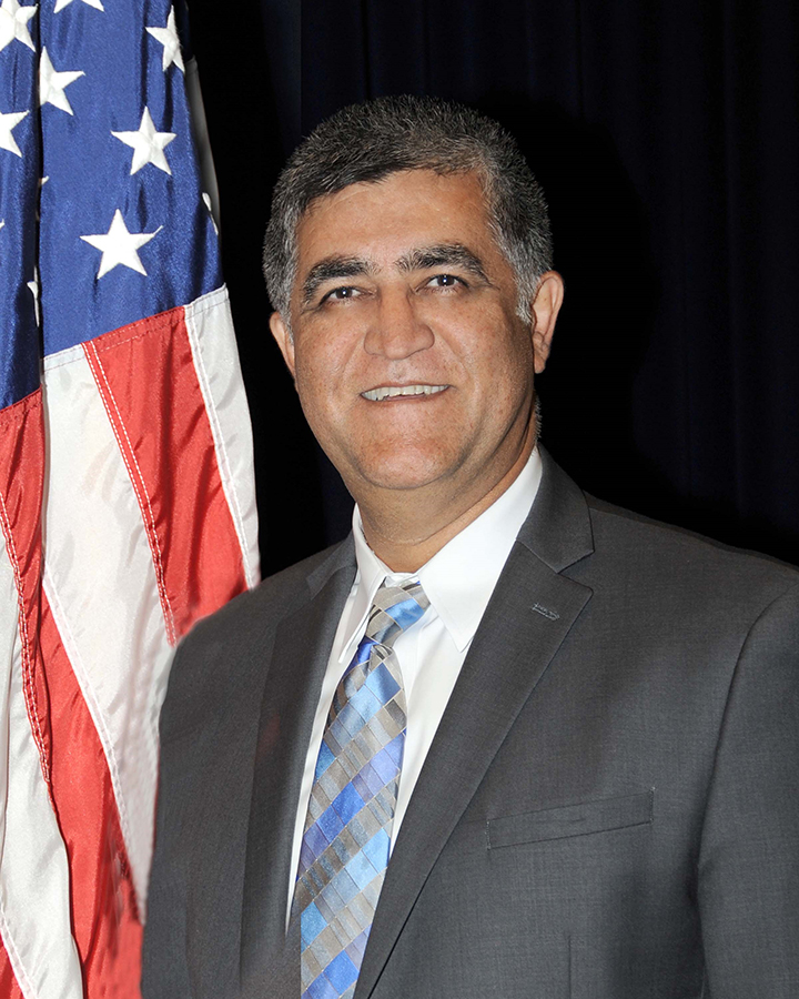 Zal Azmi formal photo in dark suit with US flag