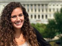Elizabeth Rule with long brown curly hair in front of the U.S. Capitol