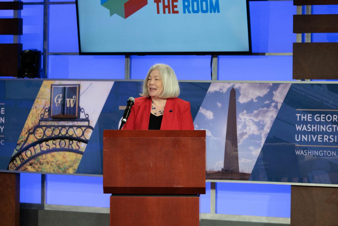 GW President Ellen Granberg standing at a podium onstage