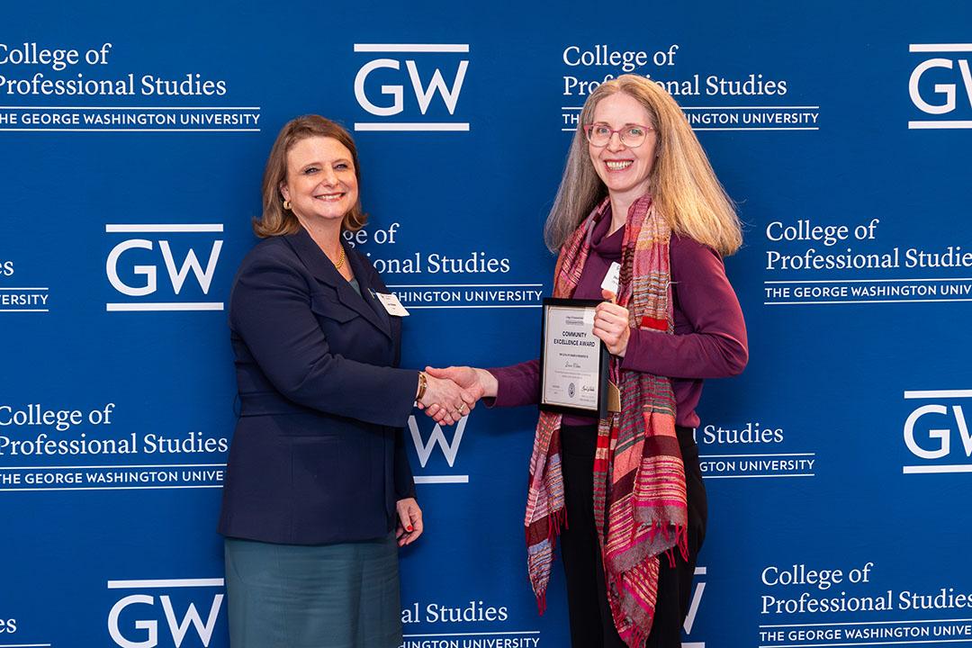 Two women with award frame in front of a GW blue background with logos.