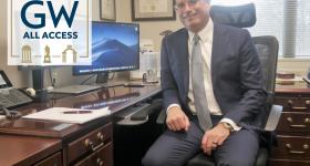 Todd Belt at his desk, GW all access logo to his left